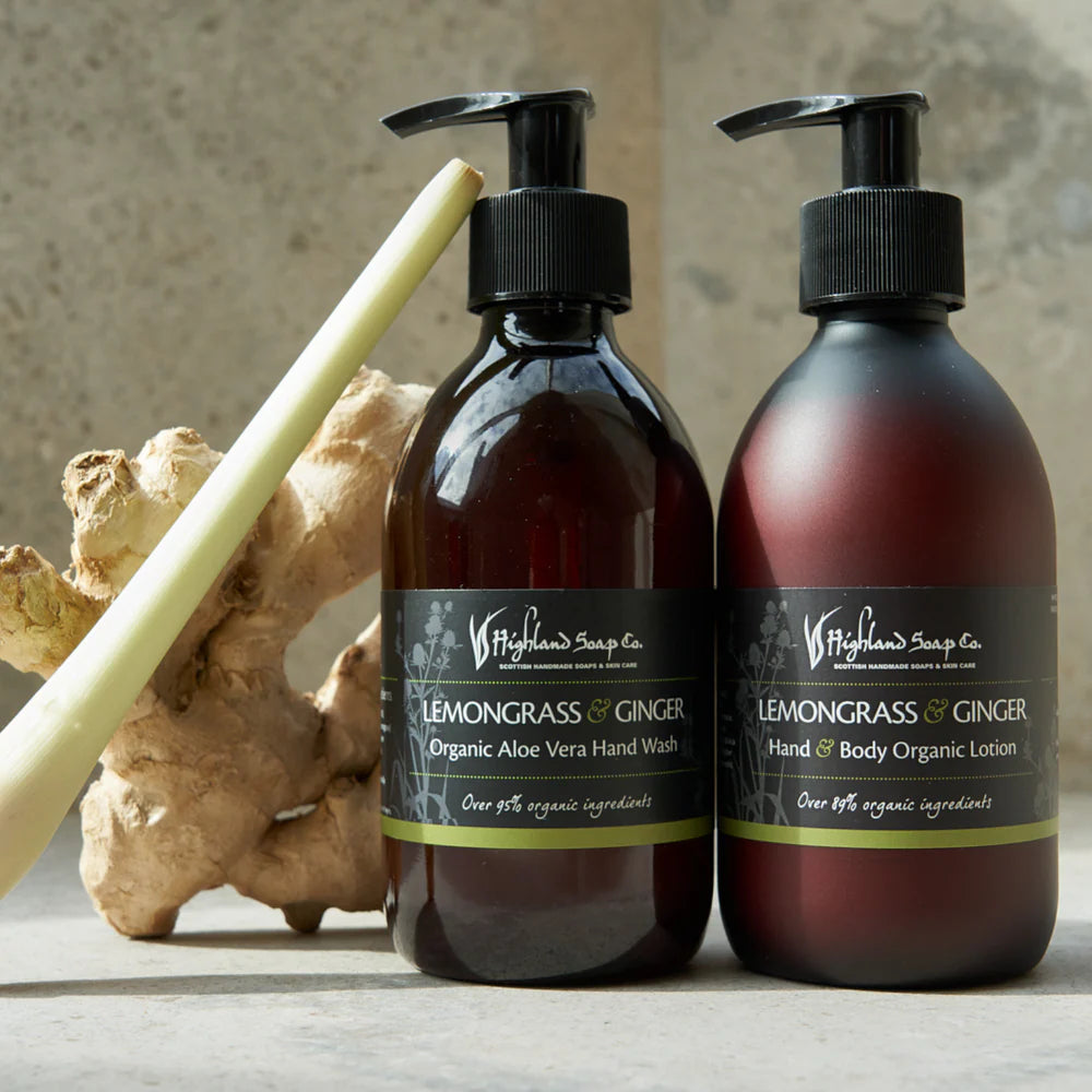 Two bottles of Highland Soap Company Lemongrass & Ginger hand wash and lotion with a piece of ginger root on a neutral background