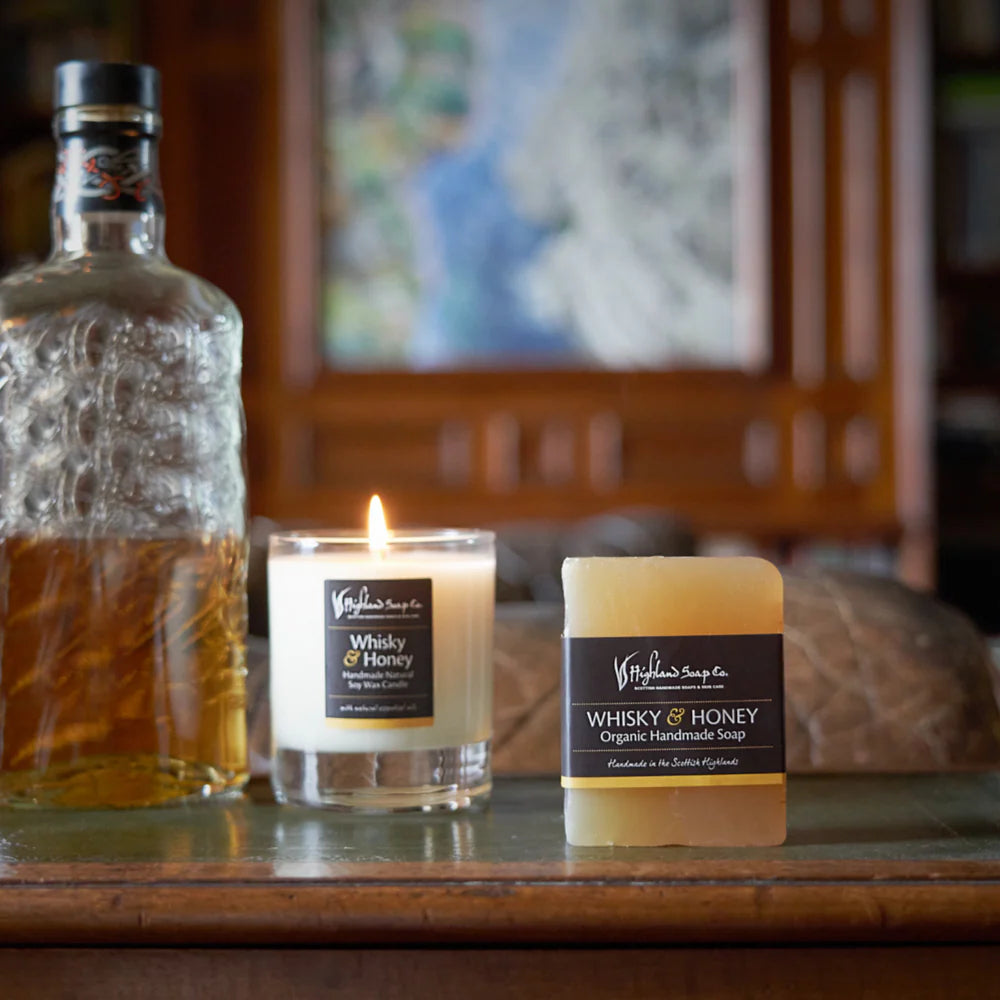 Whisky and Honey soap and candle on a wooden surface with a blurred background