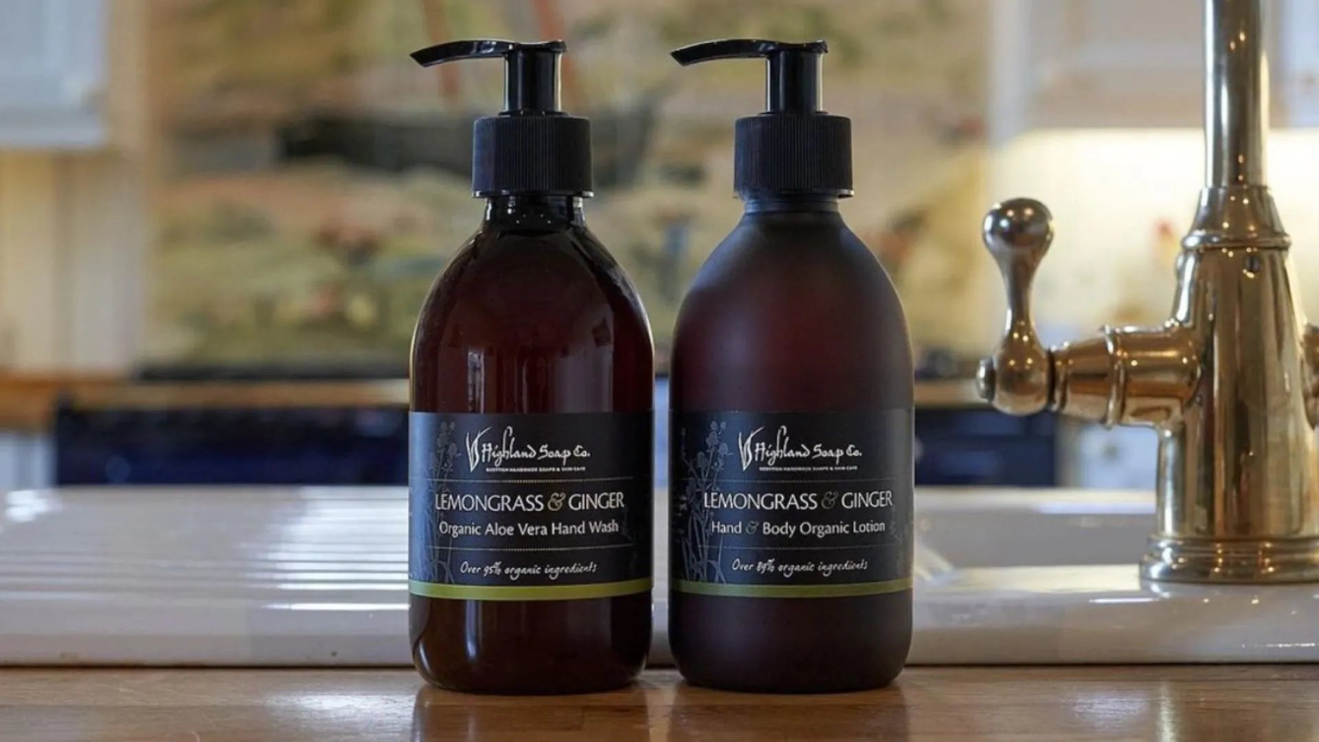 Two brown bottles of Lemongrass & Ginger products next to a tap