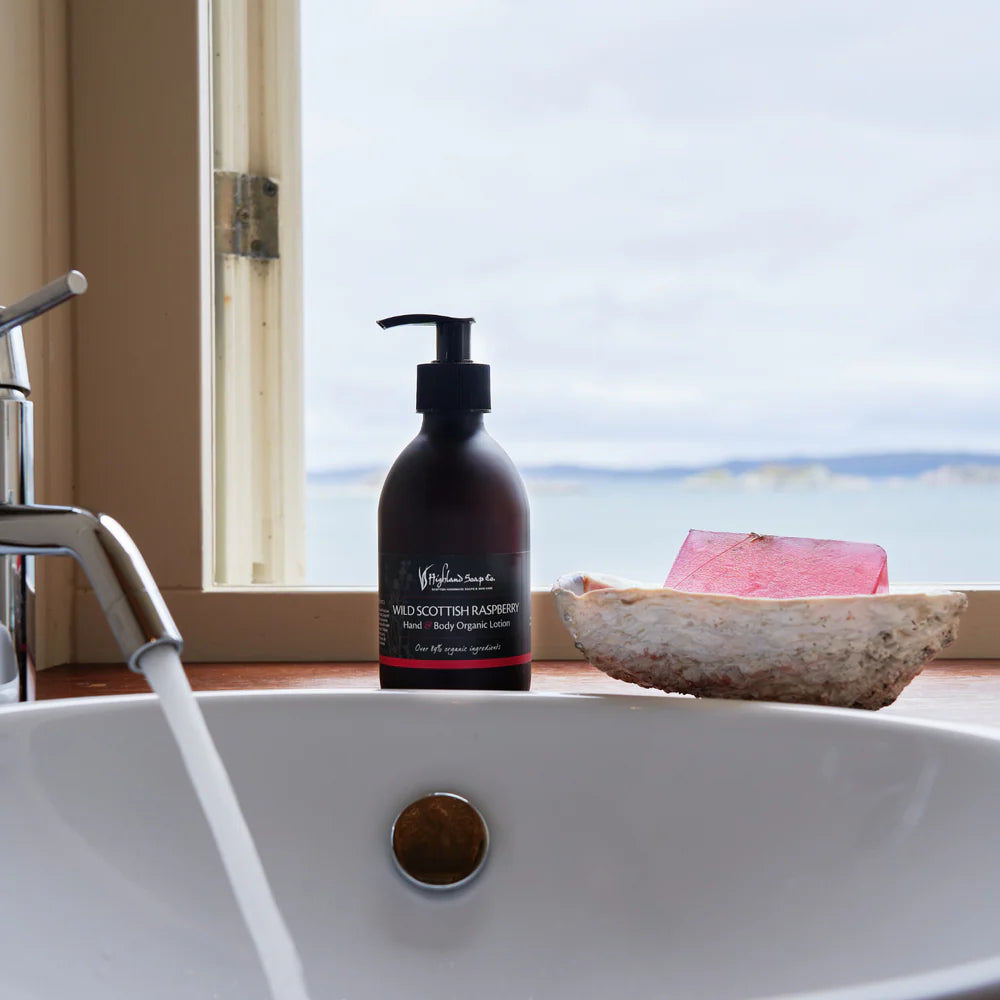 Bottle of Wild Scottish Raspberry Lotion  and Soap on a sink with a window view