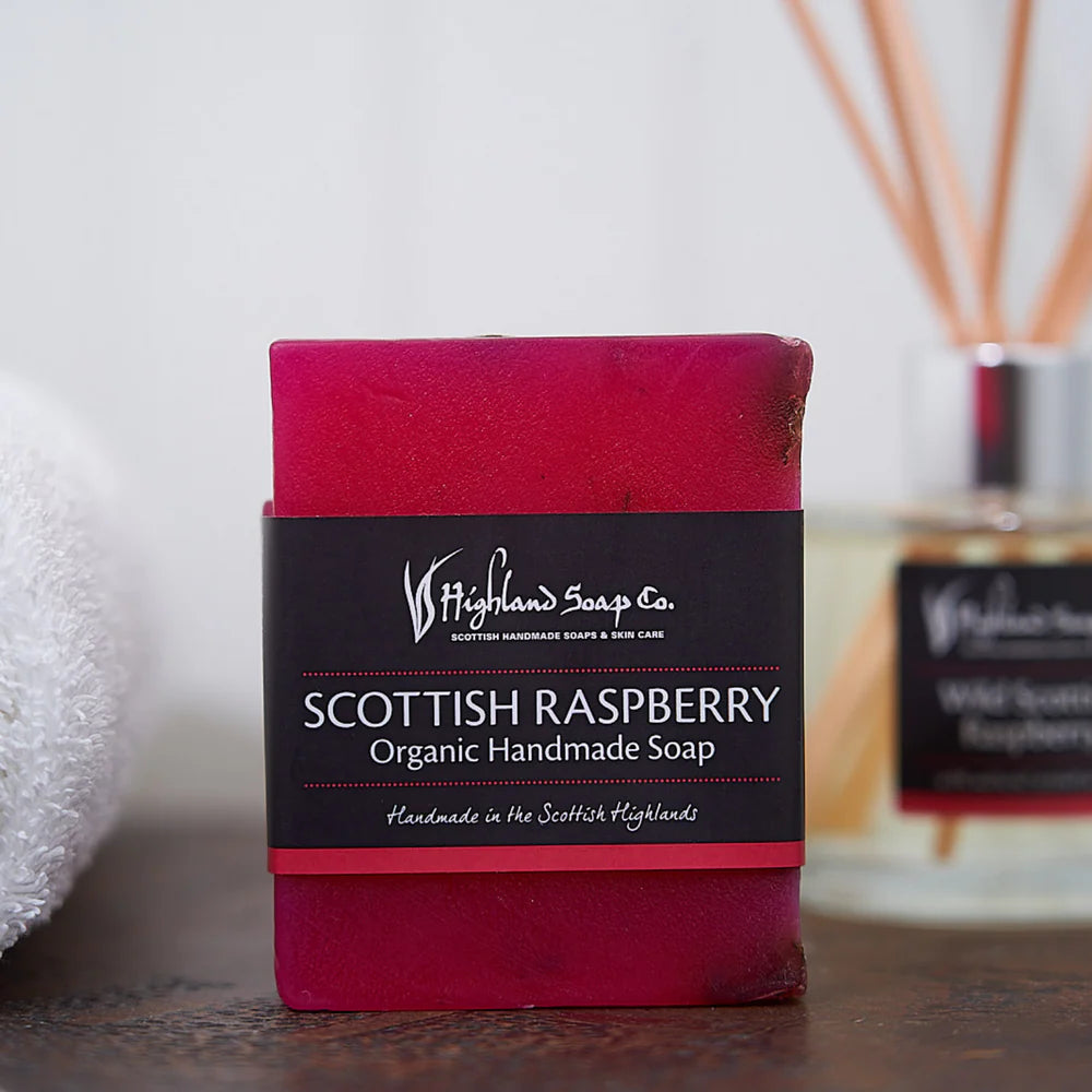 Bar of Scottish Raspberry soap with a black label on a wooden surface