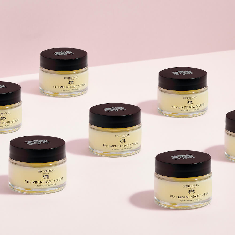 Multiple jars of Highclere Pre-Eminent Beauty Serum on a light pink background