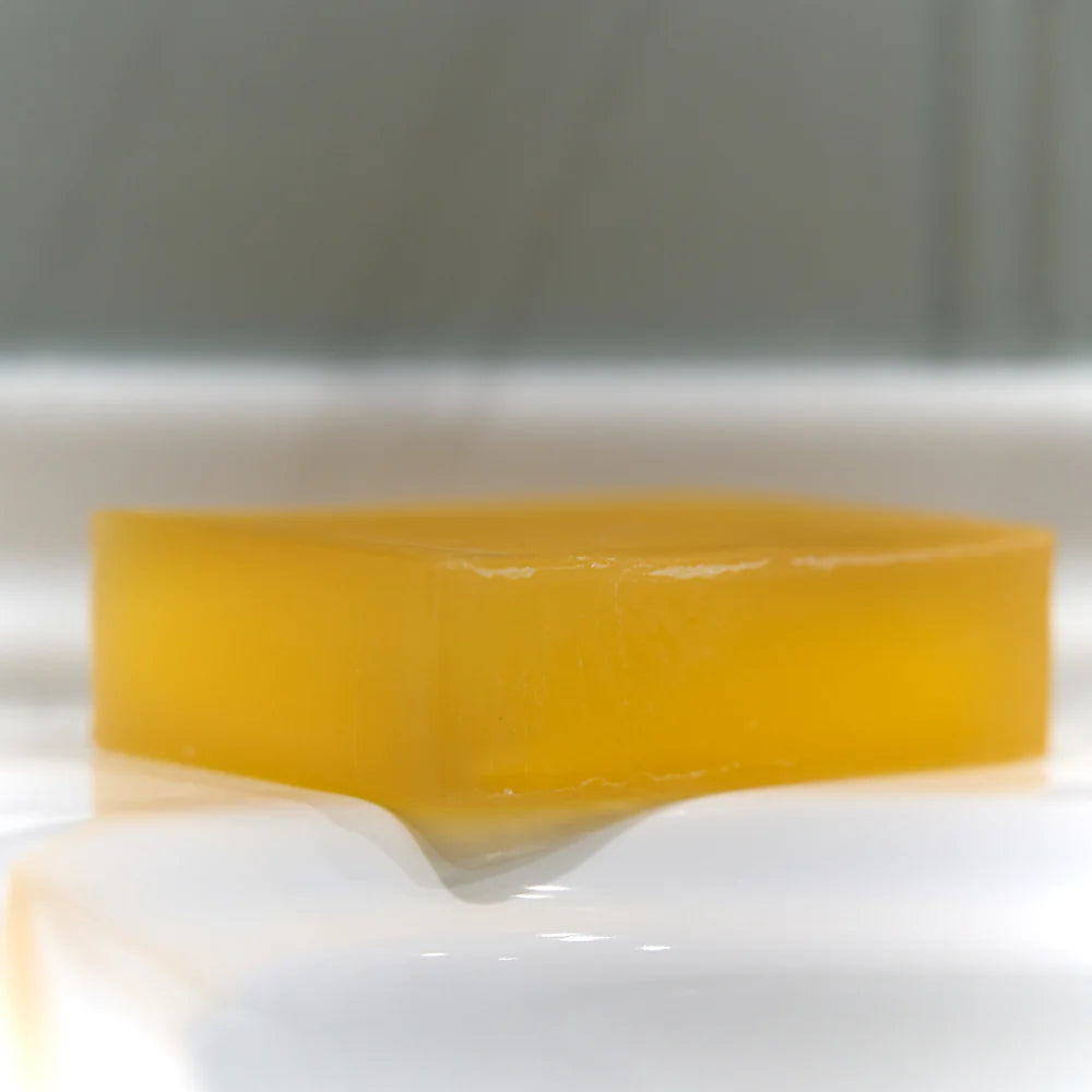 Yellow Lemongrass & Ginger Soap bar on a white surface with a blurred background